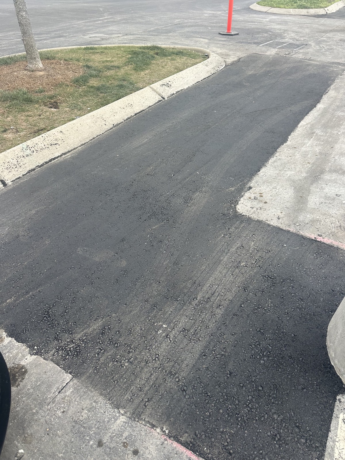 New hot-mix asphalt laid flush against the existing concrete curb and drainage pan where a failed section was removed