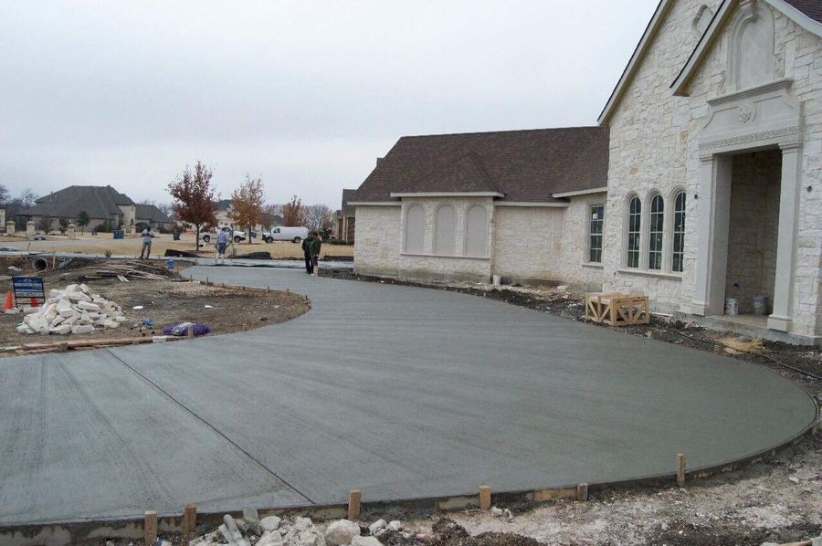 Freshly poured and finished concrete pad alongside an asphalt parking area